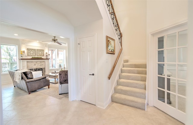 interior space with ceiling fan, a large fireplace, a healthy amount of sunlight, and lofted ceiling