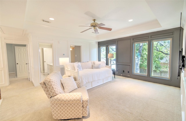 carpeted bedroom with a raised ceiling, crown molding, and ceiling fan