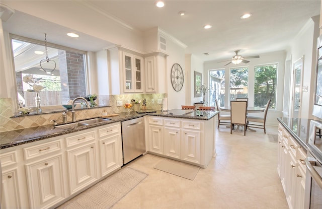 kitchen featuring tasteful backsplash, dishwasher, sink, dark stone counters, and kitchen peninsula