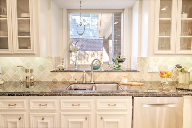 kitchen featuring dishwasher, sink, dark stone counters, and decorative light fixtures