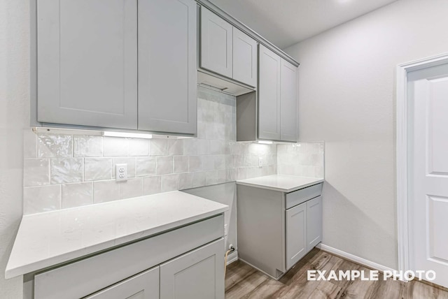 kitchen featuring tasteful backsplash, gray cabinets, light wood-style flooring, and baseboards