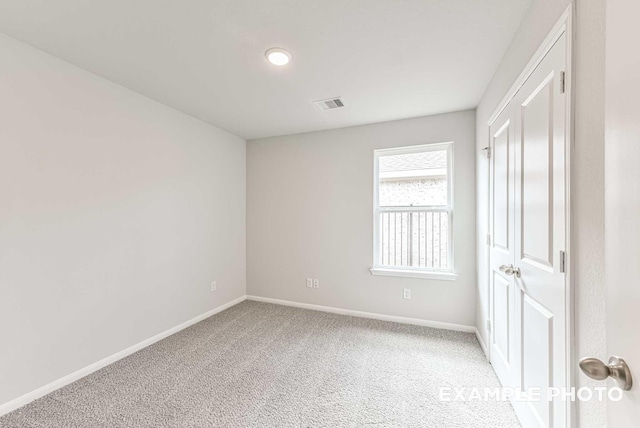 spare room featuring baseboards, visible vents, and light colored carpet