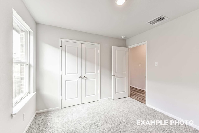 unfurnished bedroom featuring carpet, a closet, visible vents, and baseboards