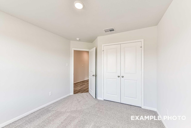 unfurnished bedroom featuring carpet floors, visible vents, baseboards, and a closet