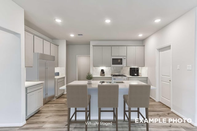 kitchen with white microwave, a sink, and gray cabinetry