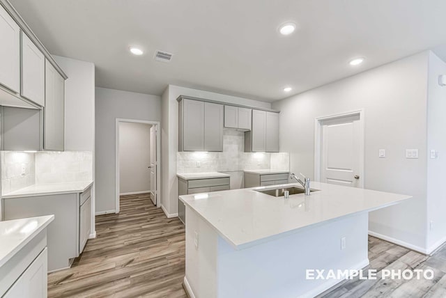 kitchen featuring light wood-style floors, a kitchen island with sink, a sink, and recessed lighting