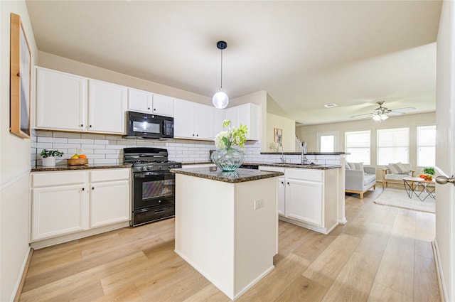 kitchen with white cabinets, kitchen peninsula, hanging light fixtures, and black appliances