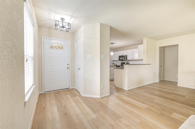 entrance foyer with an inviting chandelier and light hardwood / wood-style floors