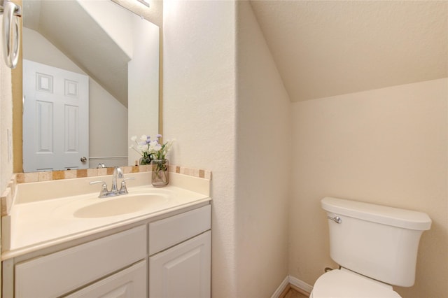 bathroom featuring vanity, lofted ceiling, and toilet