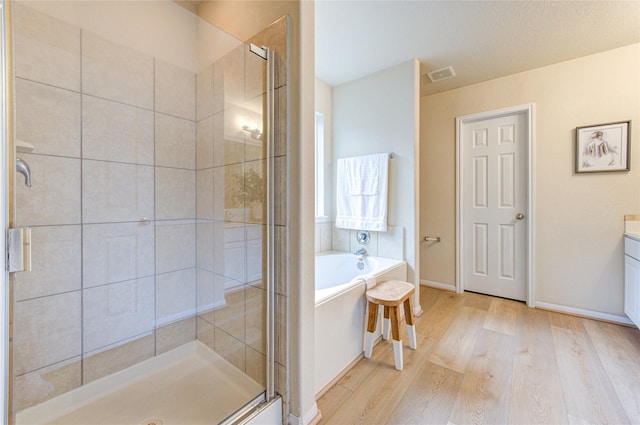 bathroom featuring wood-type flooring, shower with separate bathtub, and vanity