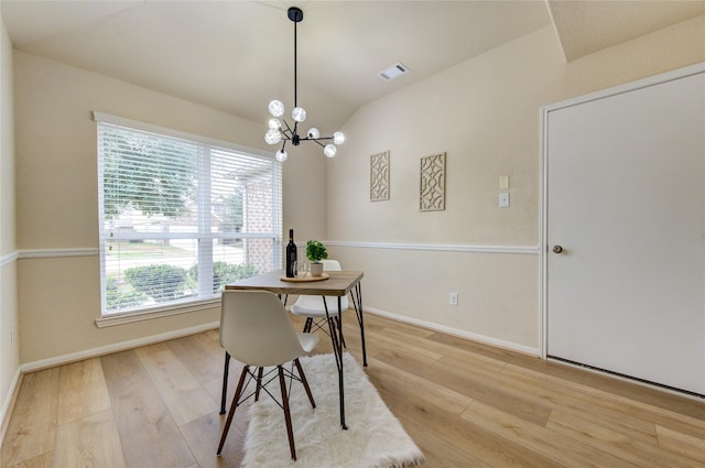 dining area with light hardwood / wood-style floors, vaulted ceiling, and a notable chandelier