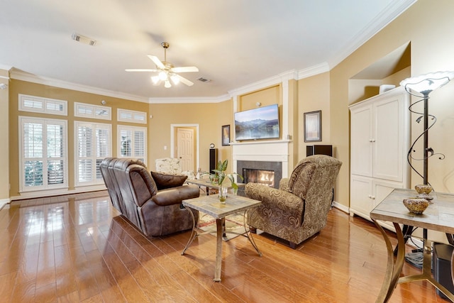 living room featuring crown molding, ceiling fan, and light hardwood / wood-style flooring