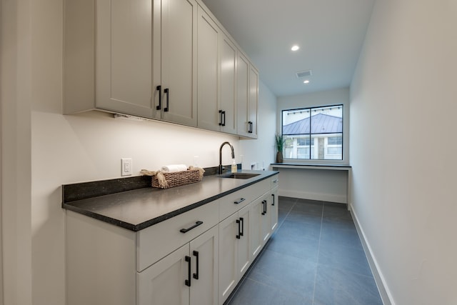 kitchen with white cabinetry, sink, and dark tile patterned floors