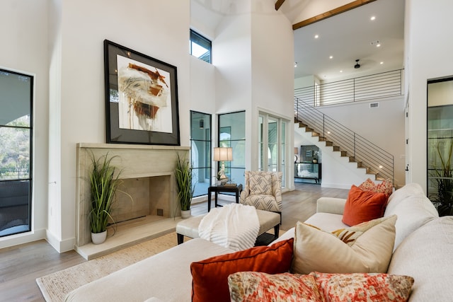 living room with hardwood / wood-style flooring, a towering ceiling, plenty of natural light, and a premium fireplace