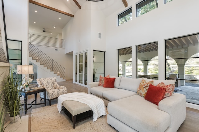 living room with a towering ceiling, beamed ceiling, and hardwood / wood-style flooring