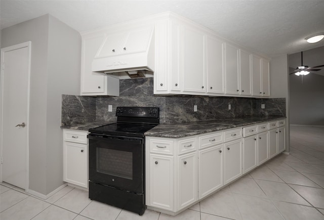 kitchen featuring premium range hood, black electric range, white cabinets, and dark stone counters