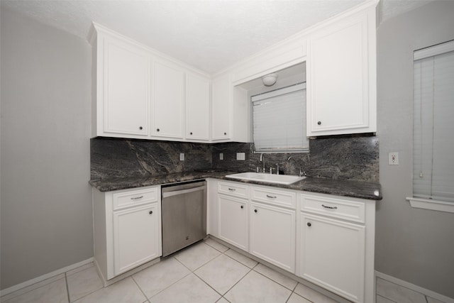 kitchen featuring white cabinetry, sink, stainless steel dishwasher, and dark stone counters