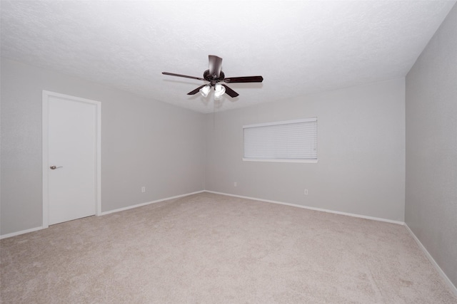 spare room featuring ceiling fan, light colored carpet, and a textured ceiling