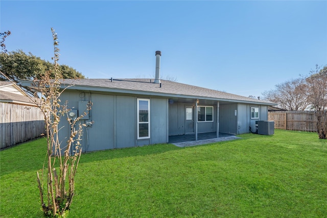 rear view of property featuring central AC unit and a lawn