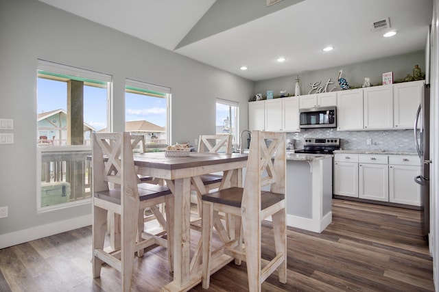 dining room featuring dark wood finished floors, visible vents, recessed lighting, and vaulted ceiling