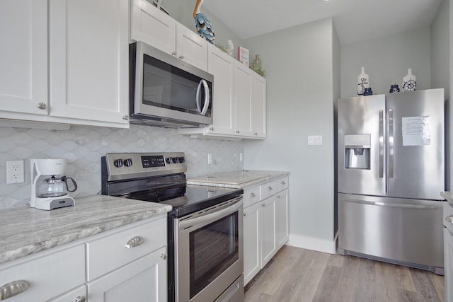 kitchen featuring light stone counters, light wood-type flooring, appliances with stainless steel finishes, white cabinetry, and tasteful backsplash
