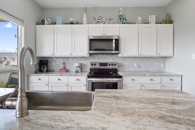 kitchen featuring decorative backsplash, white cabinets, and stainless steel appliances