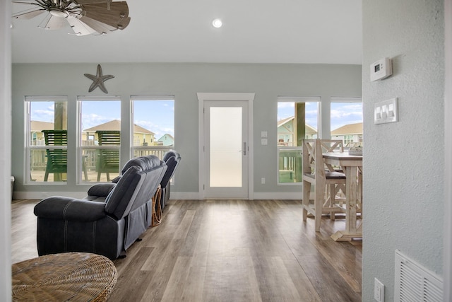 living area featuring visible vents, baseboards, a healthy amount of sunlight, and wood finished floors