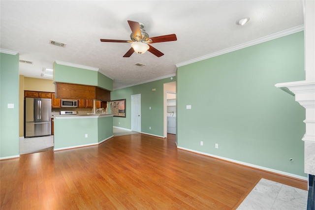 unfurnished living room with ornamental molding, washer / dryer, ceiling fan, and light hardwood / wood-style floors