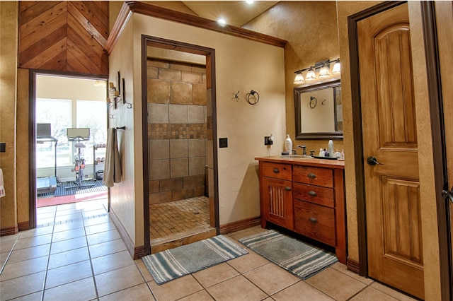 full bathroom featuring a tile shower, tile patterned floors, vanity, and baseboards
