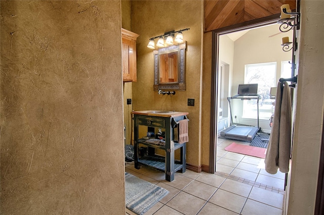 bathroom with tile patterned flooring, a textured wall, and lofted ceiling