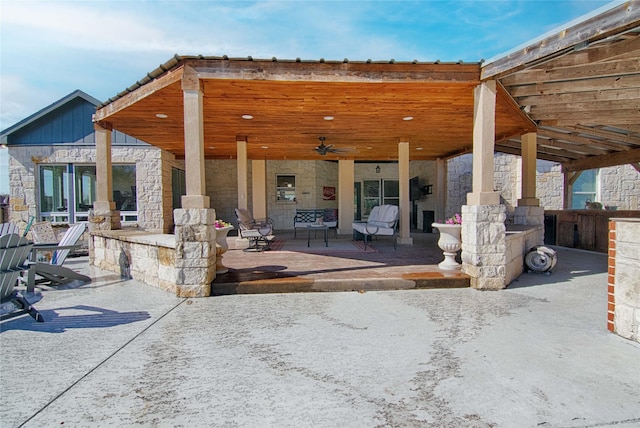 back of property featuring a ceiling fan, a patio area, and stone siding