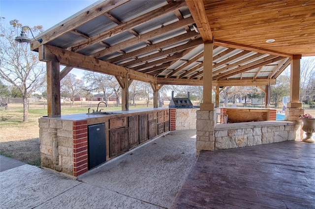 view of patio featuring an outdoor kitchen, a sink, fence, and a gazebo