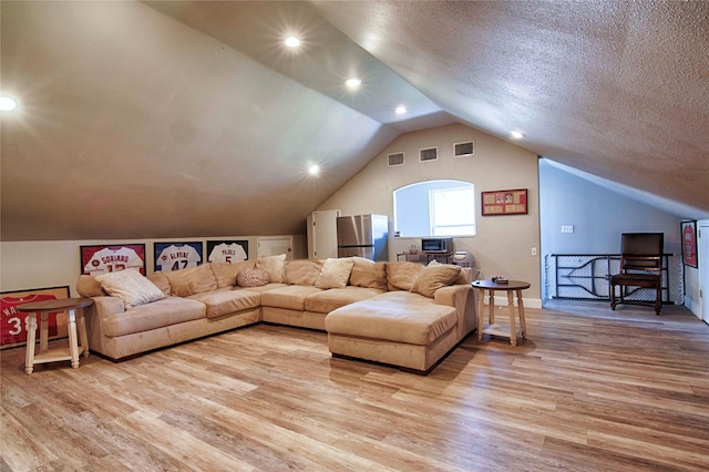 living room with visible vents, light wood-style floors, and lofted ceiling