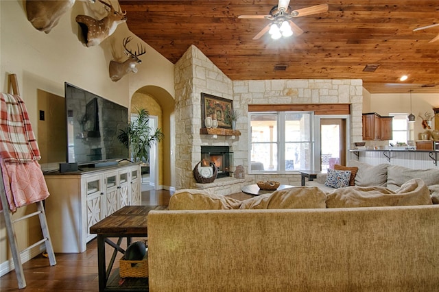 living area with a stone fireplace, dark wood-type flooring, ceiling fan, arched walkways, and wood ceiling