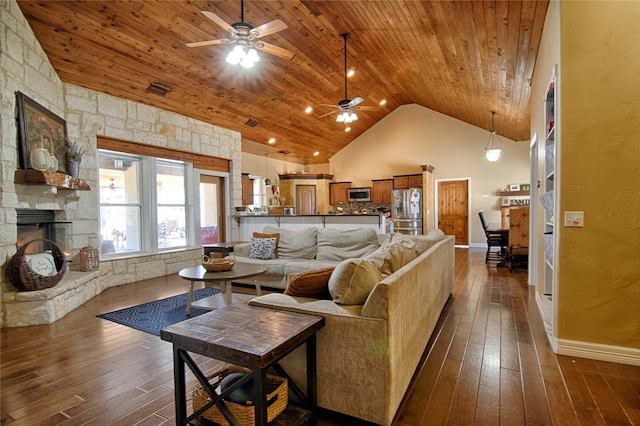 living room with baseboards, wooden ceiling, a stone fireplace, ceiling fan, and dark wood finished floors