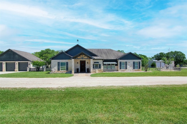 view of front facade with a front lawn, stone siding, and a garage