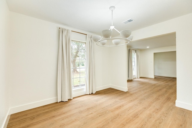 unfurnished dining area featuring a chandelier, a healthy amount of sunlight, and light wood-type flooring