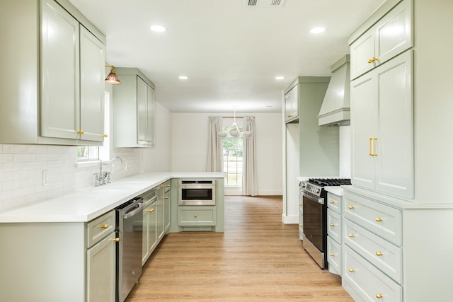 kitchen with decorative light fixtures, light wood-type flooring, gray cabinets, custom range hood, and stainless steel appliances