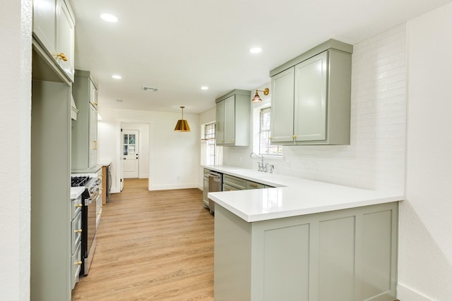 kitchen featuring tasteful backsplash, sink, hanging light fixtures, kitchen peninsula, and stainless steel appliances