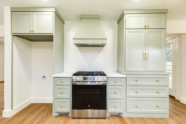 kitchen with gas stove, gray cabinetry, custom range hood, light hardwood / wood-style floors, and backsplash