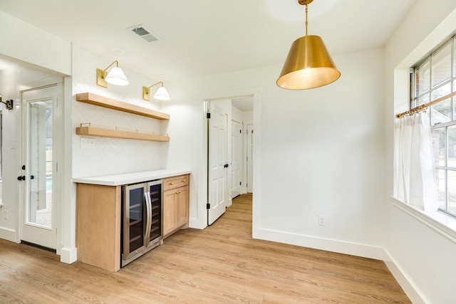 kitchen featuring wine cooler, decorative light fixtures, plenty of natural light, and light hardwood / wood-style floors