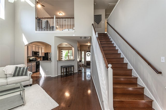 stairs featuring hardwood / wood-style floors, ceiling fan, and a high ceiling