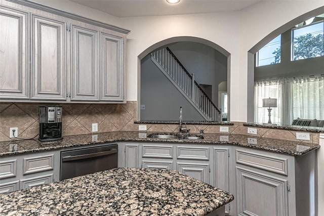 kitchen featuring gray cabinets, black dishwasher, sink, and dark stone countertops