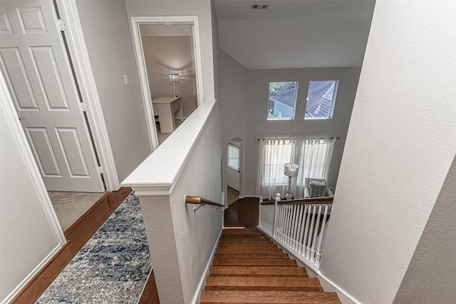 stairway with hardwood / wood-style floors and a high ceiling