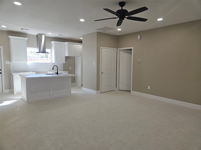 kitchen with sink, white cabinets, exhaust hood, ceiling fan, and a center island with sink