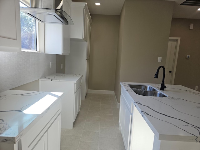 kitchen with white cabinetry, light stone countertops, sink, and exhaust hood