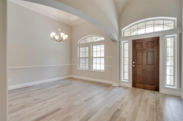 entrance foyer featuring an inviting chandelier, crown molding, and light hardwood / wood-style flooring