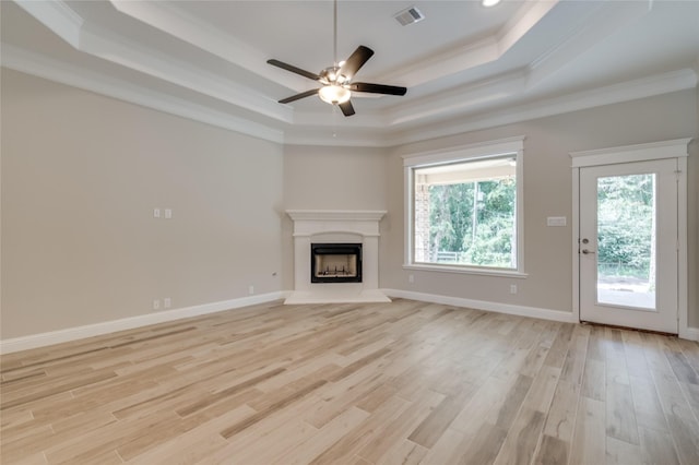 unfurnished living room featuring ornamental molding, a tray ceiling, and light hardwood / wood-style floors