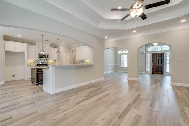 kitchen with tasteful backsplash, white cabinets, hanging light fixtures, kitchen peninsula, and crown molding