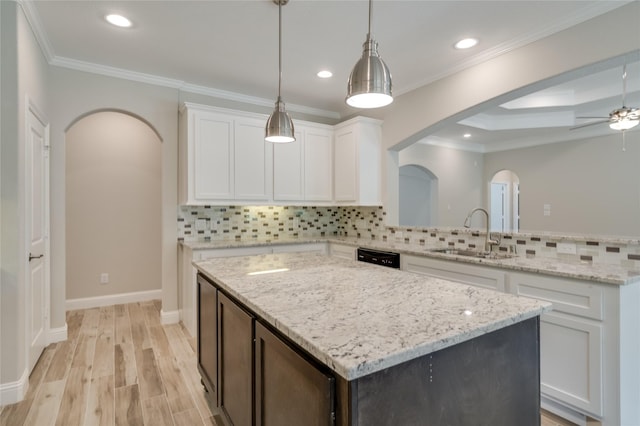 kitchen featuring sink, crown molding, decorative light fixtures, a center island, and white cabinets